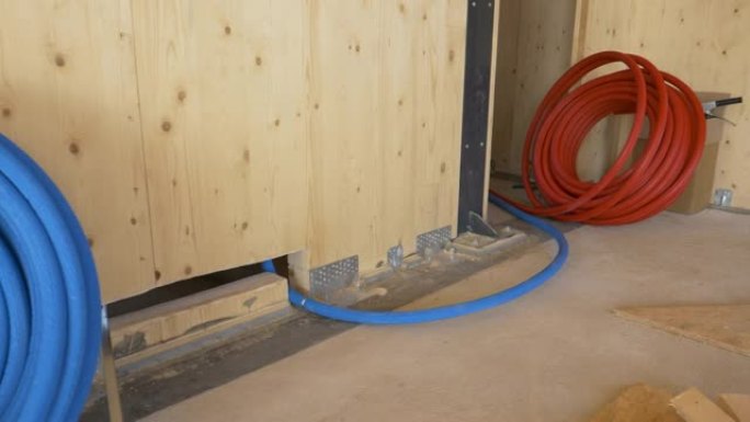 特写: 一卷蓝色橡胶管在木墙下面铺开。