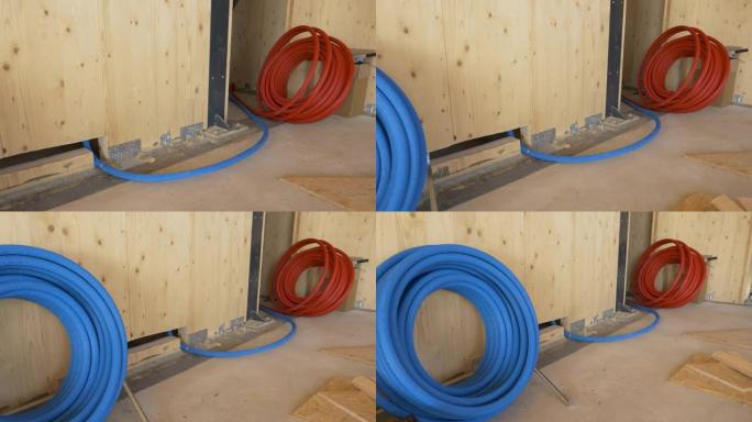 特写: 一卷蓝色橡胶管在木墙下面铺开。