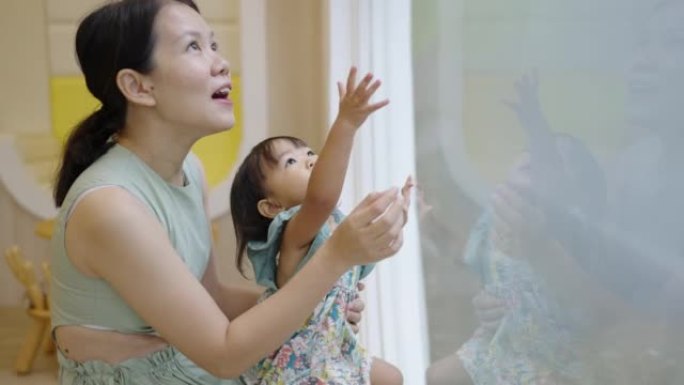 Asian mother showing her daughter a butterfly at t