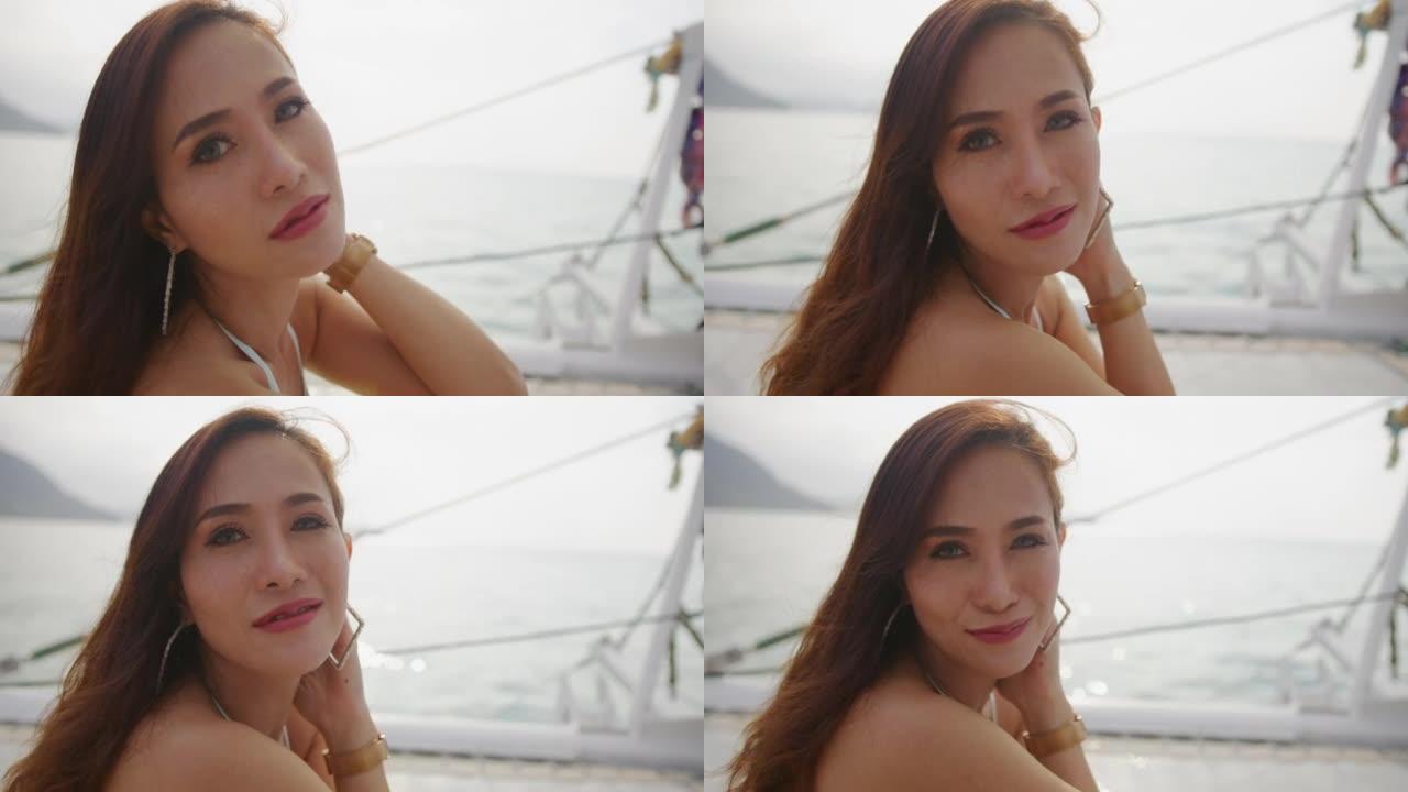 美丽的女人在日落时在游艇上放松，对镜头微笑