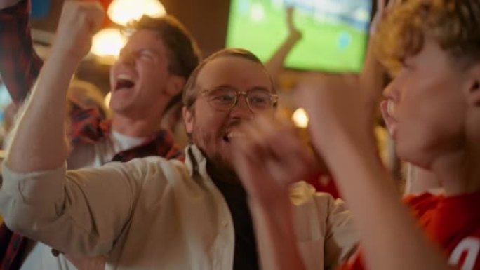 一群朋友在体育酒吧观看电视直播足球比赛。快乐的球迷欢呼雀跃。年轻人庆祝球队进球并赢得世界杯足球赛。慢