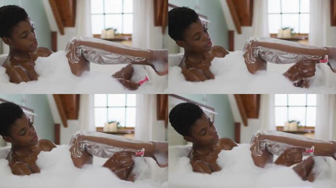 非裔美国迷人的女人在浴室的泡沫浴缸里刮腿