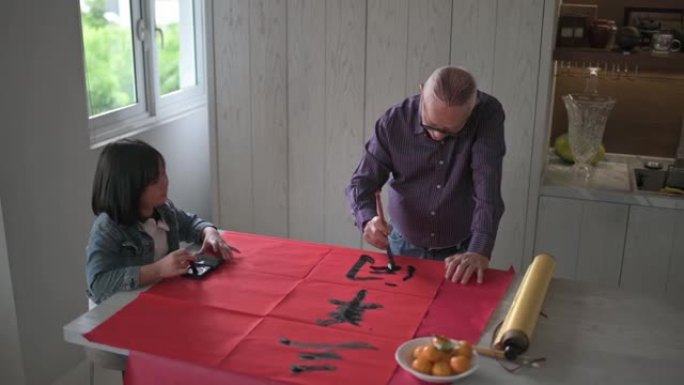 亚洲中国年轻女孩帮助和学习她的祖父写中国书法