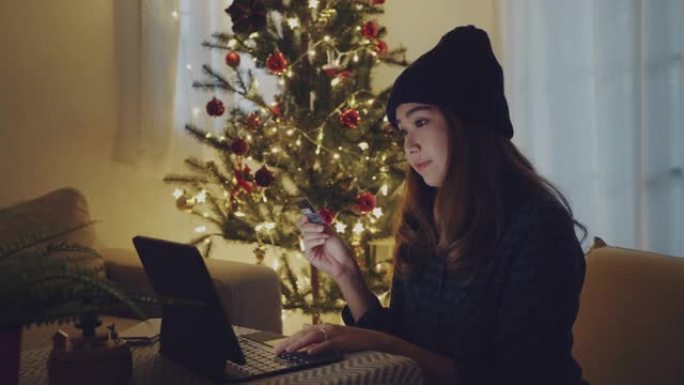 年轻女子在圣诞节假期在家用信用卡在线购物。