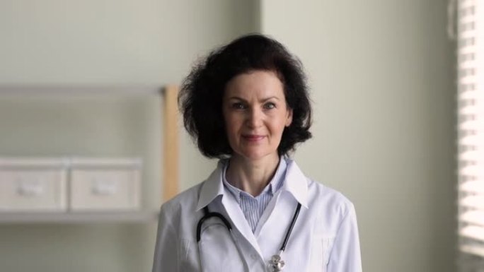 经验丰富的成熟女医生穿着白色长袍在诊所摆姿势