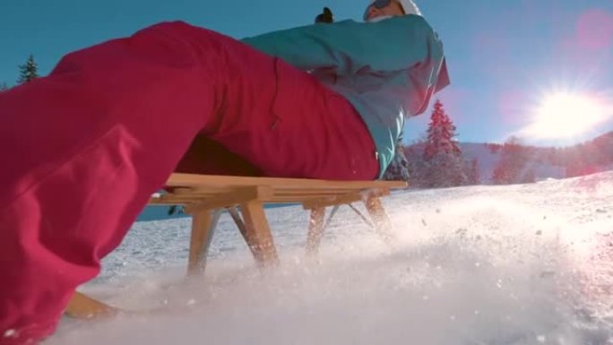 低角度: 在Kranjska Gora度假的开朗女人在雪山上雪橇。