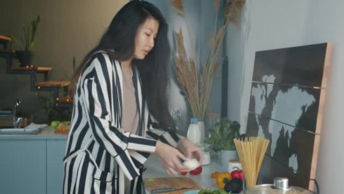 快乐的亚洲女人在厨房里做饭，微笑着忙着做饭