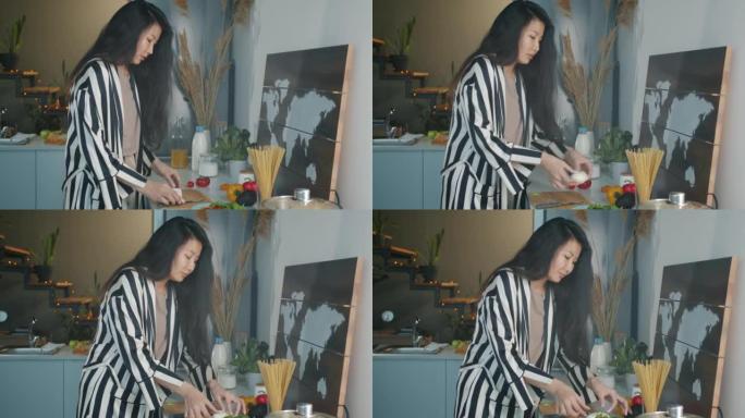 快乐的亚洲女人在厨房里做饭，微笑着忙着做饭