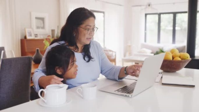 爱心，关怀和深情的祖母在笔记本电脑上阅读，与孙子保持联系。资深拥抱孙女，享受在线教育计划。奶奶对自闭