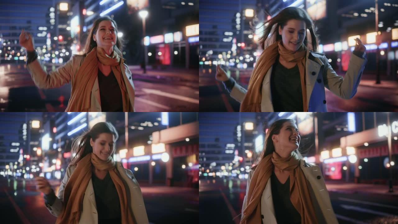 一个穿着风衣的幸福美女的肖像在夜晚霓虹灯的现代城市街道上行走。迷人的女性微笑着跳来跳去，兴奋地来到城