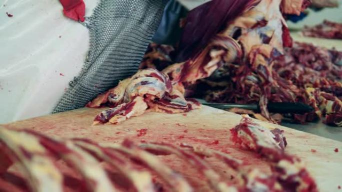 一位屠夫在肉类包装厂工作时切肉。