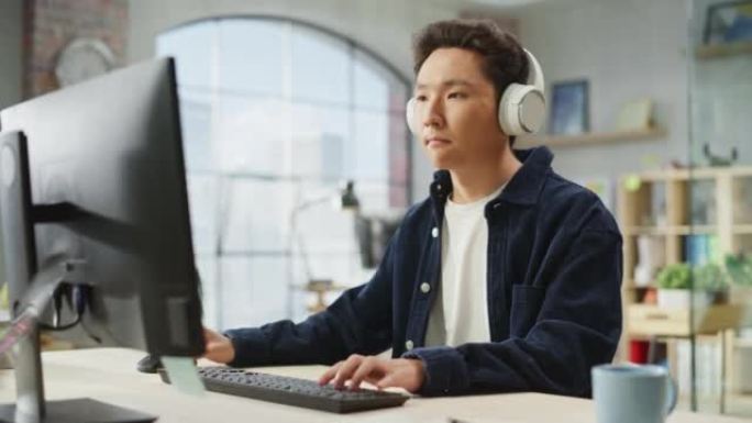 白天在现代办公室里用电脑工作的亚洲男性员工的肖像。客户支持代理在使用耳机时回答请求。手持镜头。