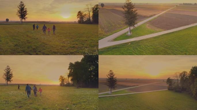 空中年轻家庭在日落时在草地上奔跑的乐趣