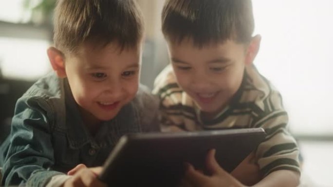 两个亚洲男性孩子的肖像在周末在他们的房间里使用数字平板电脑。两个可爱的兄弟姐妹在线观看教育内容，分享