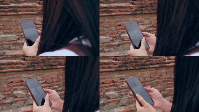 特写年轻的亚洲背包客博主女人随意看手机幻灯片上的屏幕，看老城旅行中的照片上传图片。