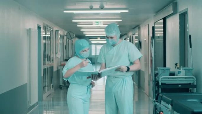 两名身穿外科制服的医生正在浏览病历