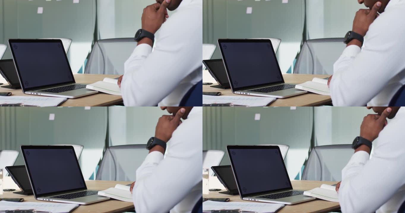 非裔美国商人在现代办公室使用带黑屏的笔记本电脑
