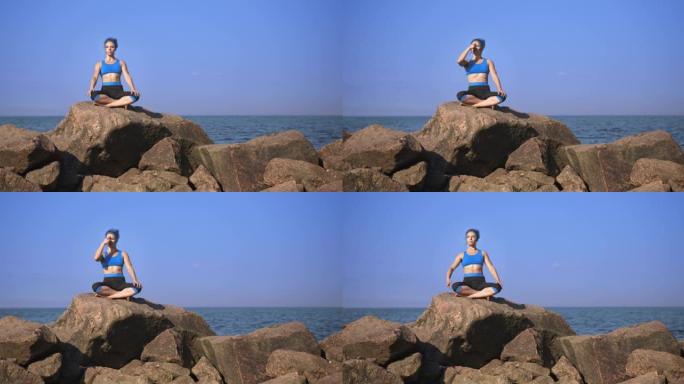 一位年轻漂亮的运动女子，有着绿松石般的头发，正在做呼吸运动，坐在鹅卵石上，靠着大海和天空