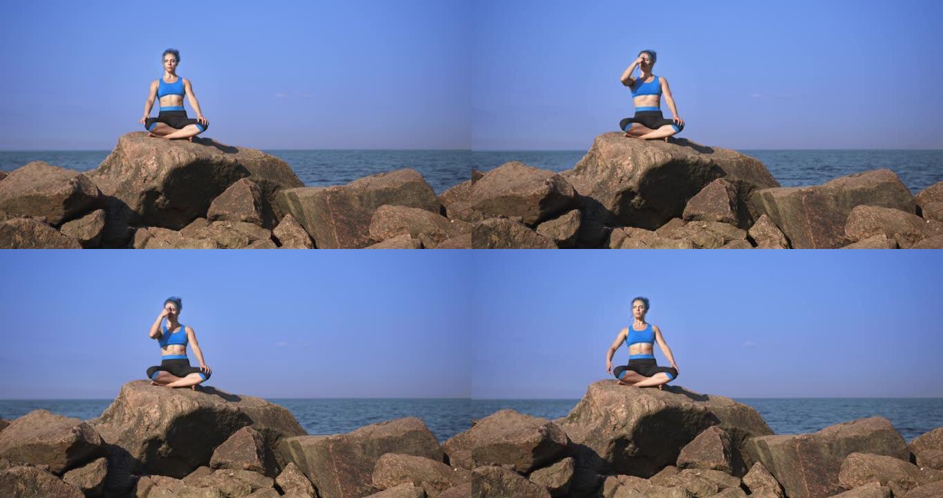 一位年轻漂亮的运动女子，有着绿松石般的头发，正在做呼吸运动，坐在鹅卵石上，靠着大海和天空