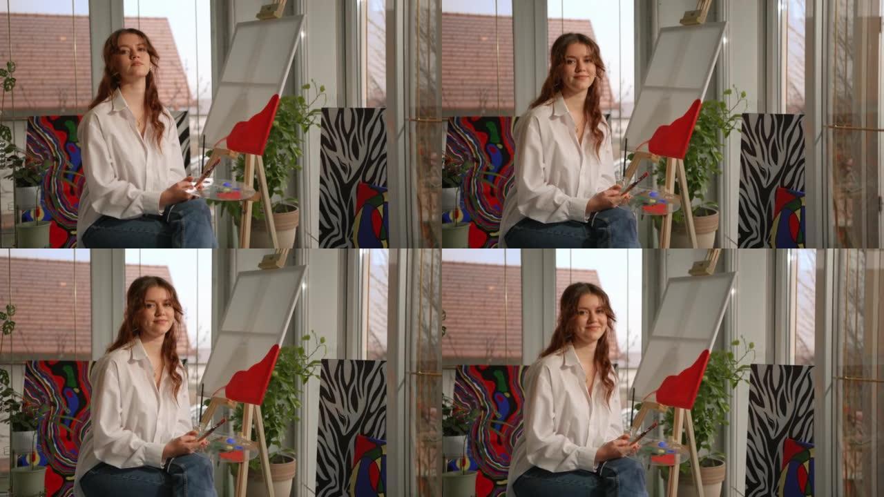一位年轻女画家的SLO MO肖像在她的工作室摆姿势时微笑