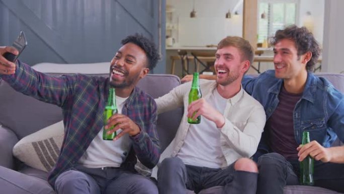 多元文化组男性朋友在家坐沙发喝啤酒摆姿势自拍