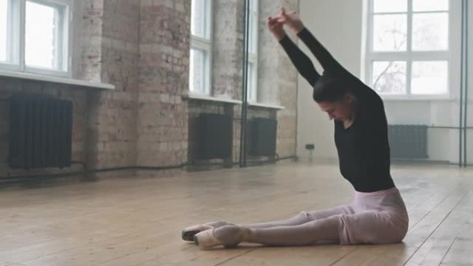 优雅的芭蕾舞演员在地板上做伸展运动