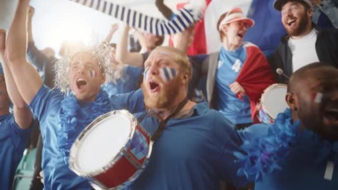 体育馆大事件: 三个不同的球迷，脸上涂着彩绘的脸欢呼，敲鼓，大笑，开心，为足球队获胜而呐喊。人们庆祝