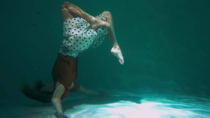大气拍摄的年轻美丽优雅的舞者女人做现代舞动作在水下慢动作下向后翻转。