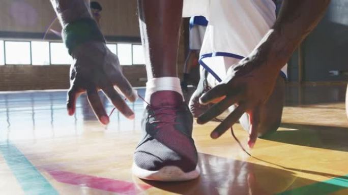 非裔美国男子篮球运动员在团队背景下系鞋带