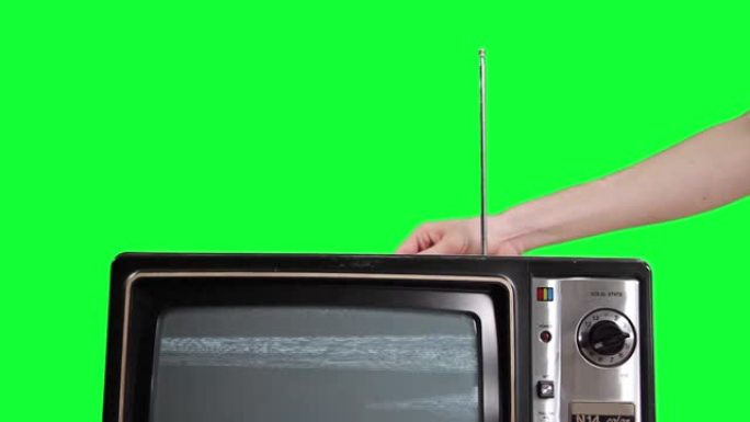 男人在绿色背景上调整蓝屏旧电视的天线。