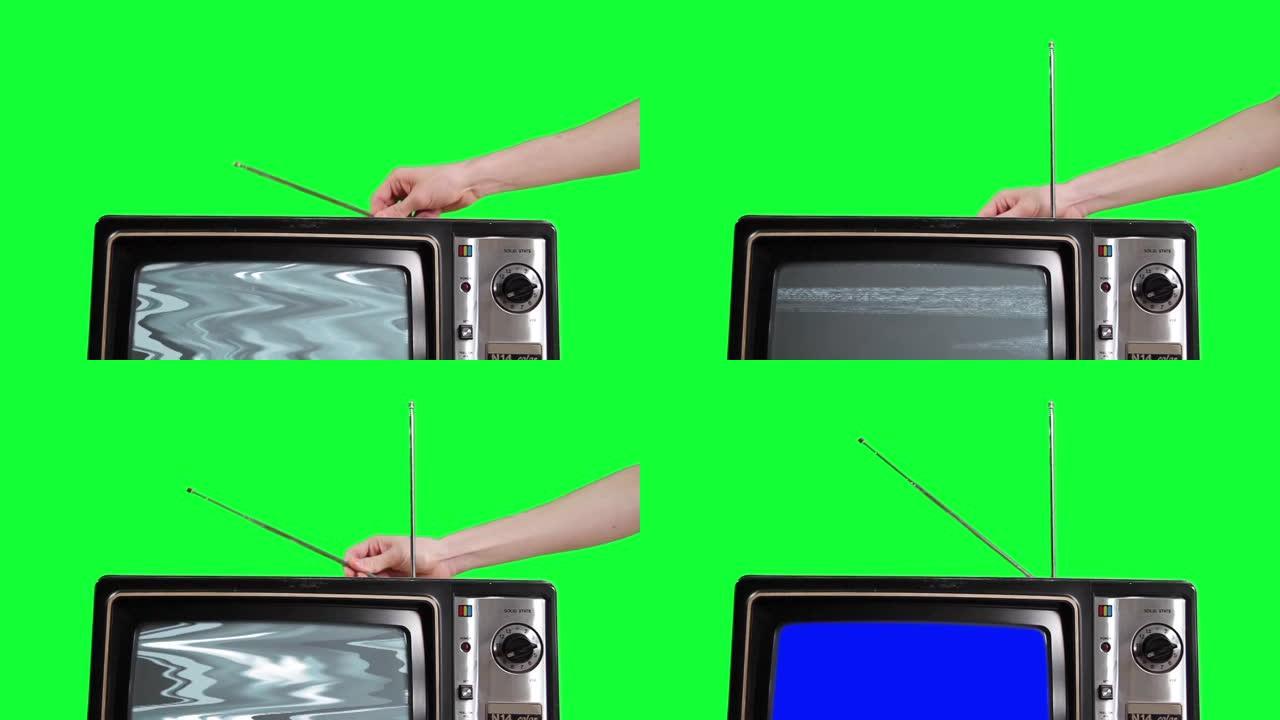 男人在绿色背景上调整蓝屏旧电视的天线。