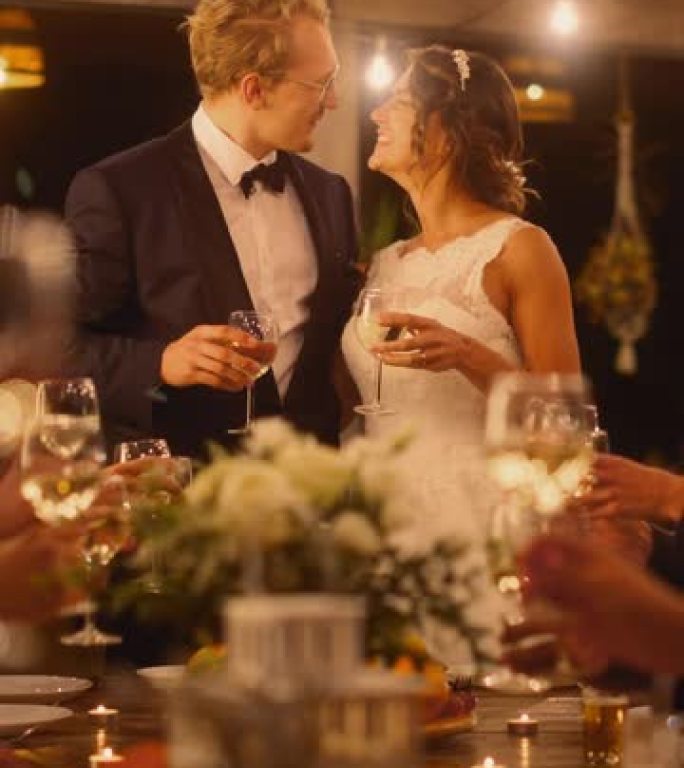 垂直屏幕: 美丽的新娘和新郎在晚会上庆祝婚礼。新婚夫妇提议为幸福的婚姻干杯，与最好的多种族多元朋友站
