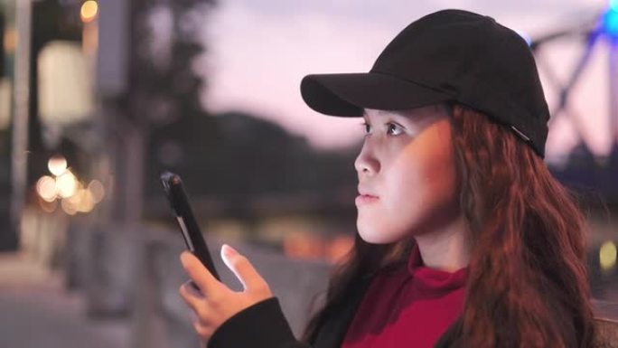 一个迷人的年轻亚洲少女使用手机、信息和浏览互联网的肖像。