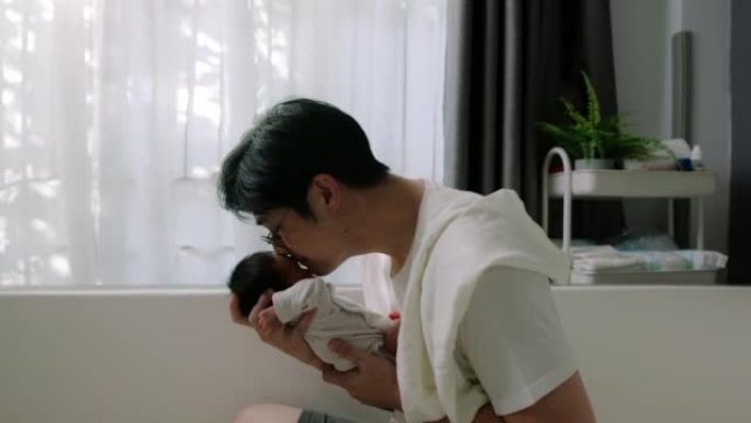 新爸爸抱着婴儿。父亲身份。他在家里与婴儿保持联系并尝试学习。
