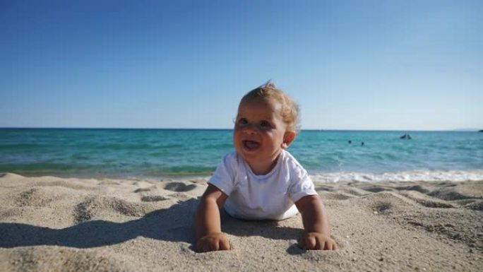 家庭度假期间，快乐微笑的蹒跚学步的男婴躺在沙滩上的真实照片