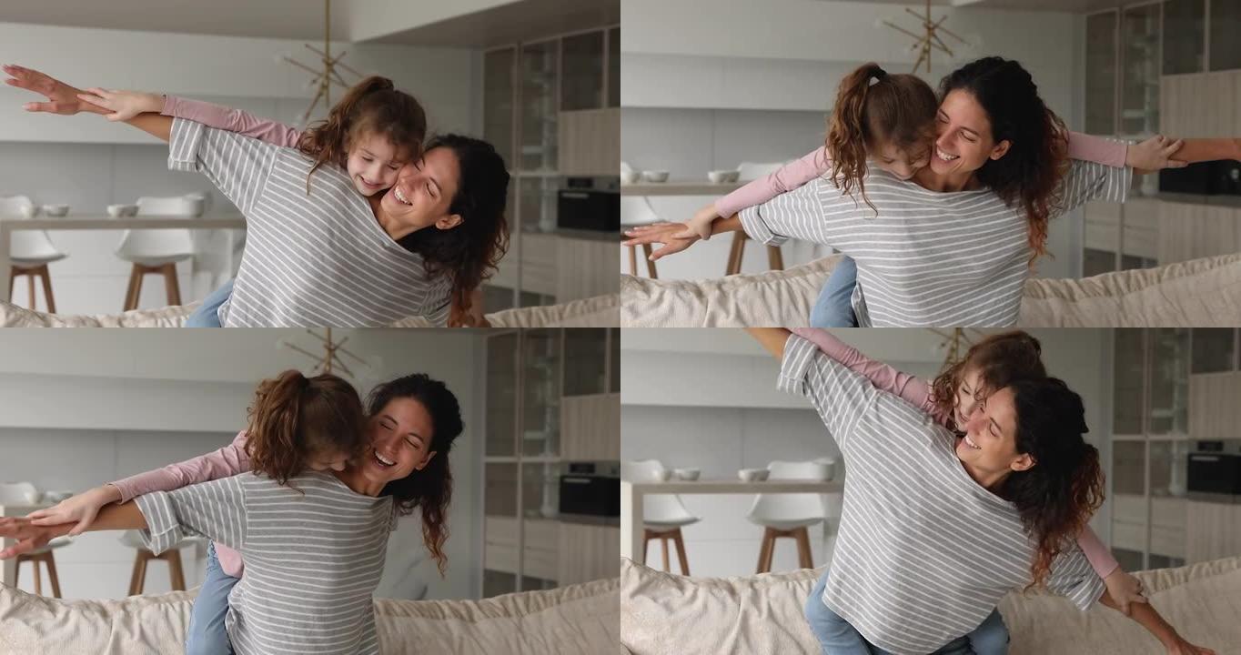 女人背着女儿像飞机翅膀一样张开双臂在室内玩耍