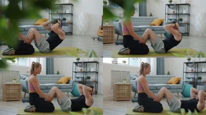 帅哥做仰卧起坐的慢动作和女朋友在家训练腹肌