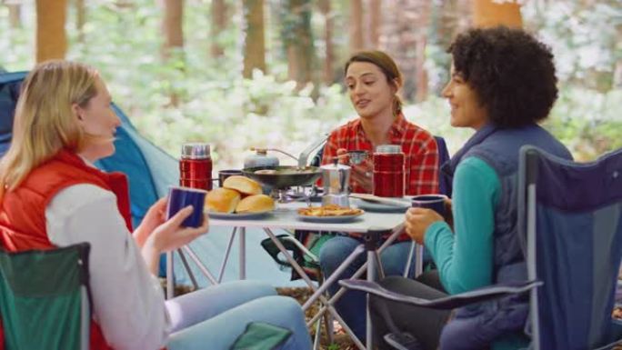 一群女性朋友在森林露营度假做饭，一起坐在帐篷旁喝咖啡-慢动作拍摄