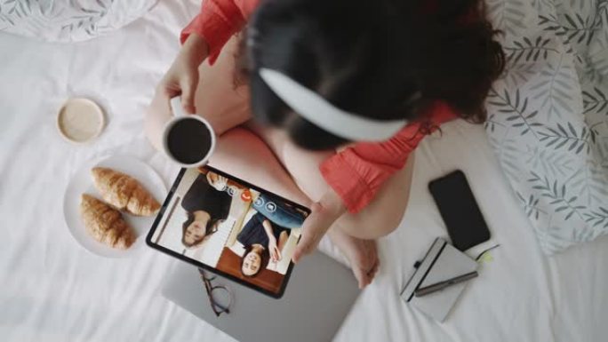 女人与她的朋友在数码平板电脑上视频聊天的顶部视图