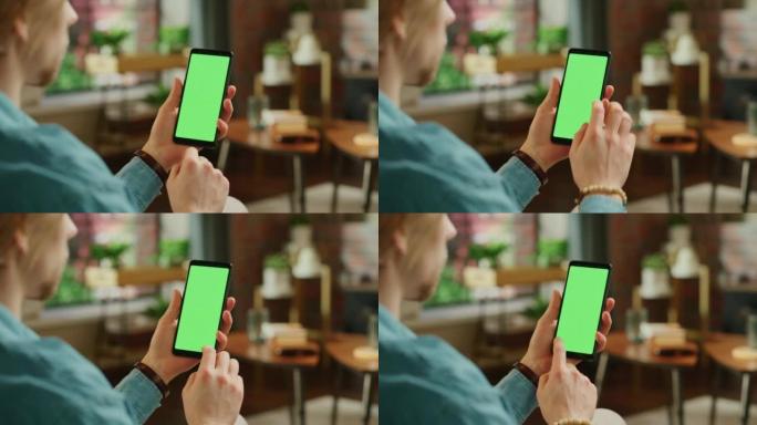 男子在显示屏上点击和滑动，并在带有绿屏模拟显示的智能手机上滚动供稿。男性在家休息，在移动设备上查看社