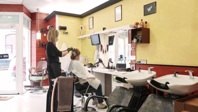 在新型冠状病毒肺炎时间为客户工作的发色师的宽视频拍摄