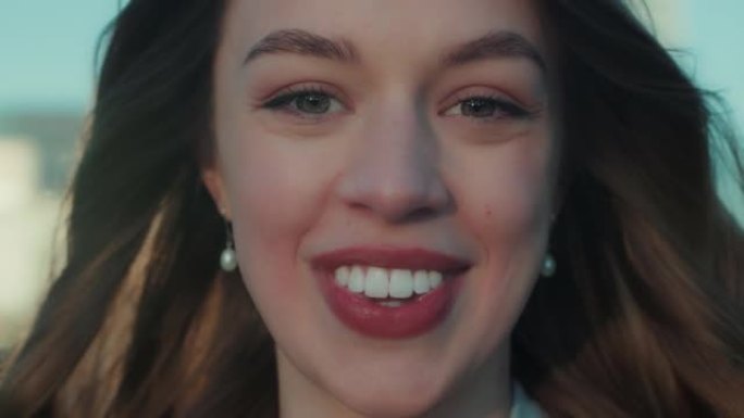 超级特写肖像快乐美丽的25-30白种人女人在日落时微笑在相机，风在头发慢动作。