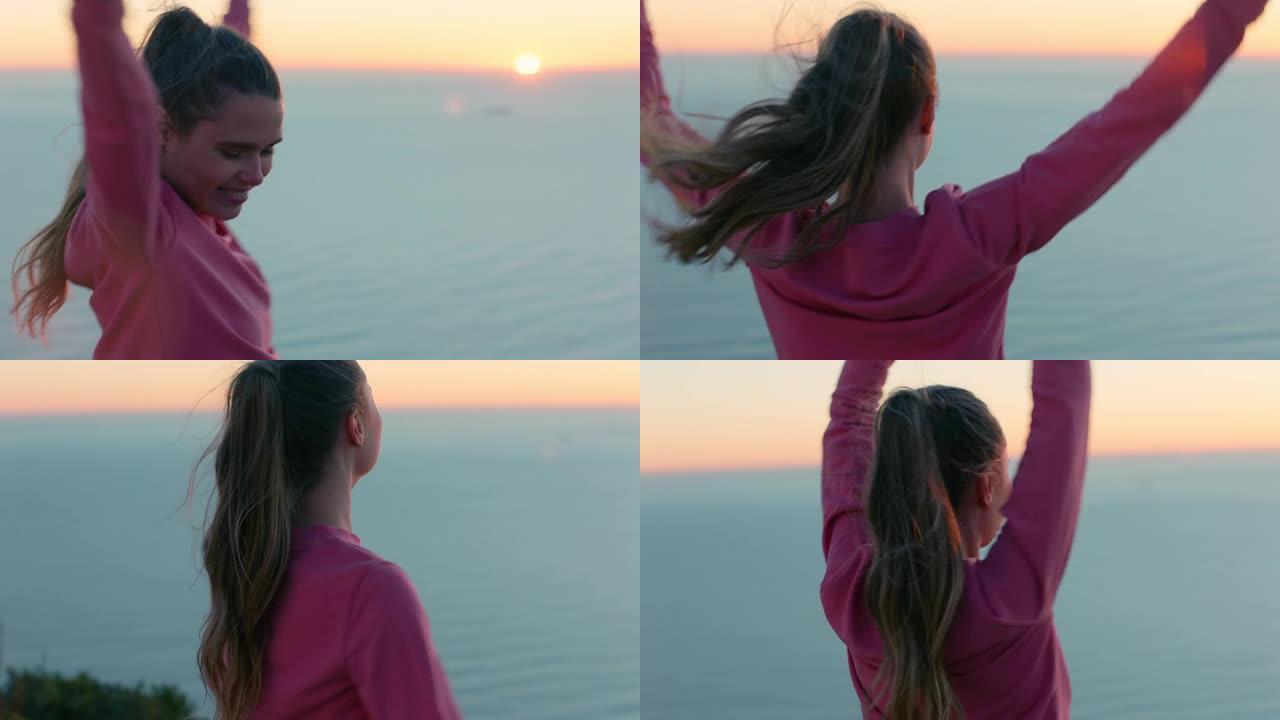 快乐的女人，双臂高举在山顶上享受自由庆祝成就女孩日落时看着美丽的海景