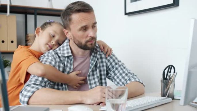 善良的小女孩拥抱不幸的父亲，父亲正在家里用电脑工作