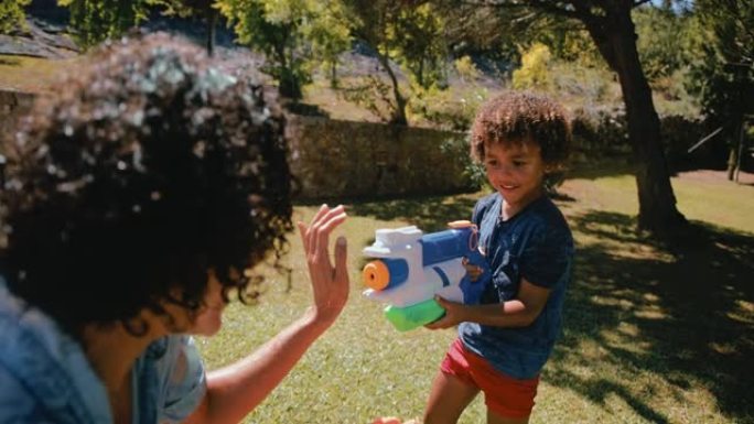 小男孩和母亲在花园里玩水枪