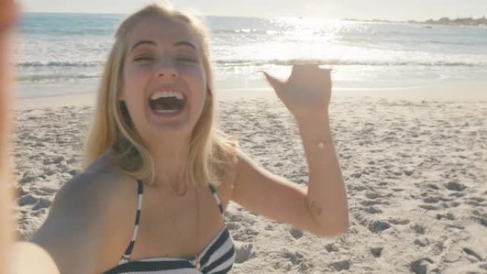美丽的女人在海滩上视频聊天女孩挥舞着相机分享暑假，用智能手机展示旅行冒险享受快乐的假期体验