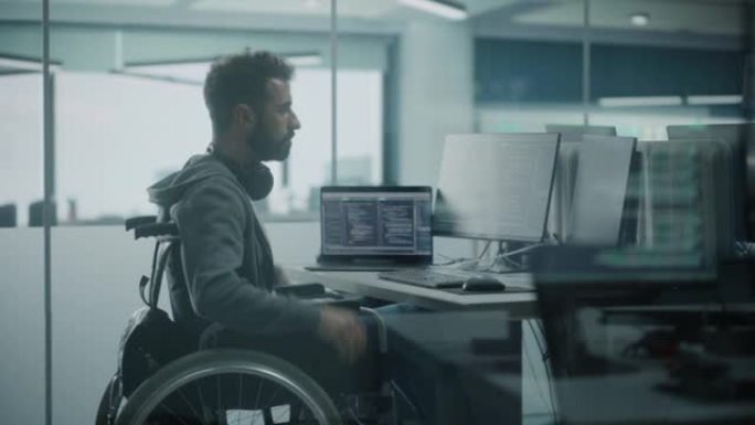 残障友好办公室: 出色的残疾IT程序员在台式计算机上工作的轮椅。男性专家创建励志软件。工程师开发创新