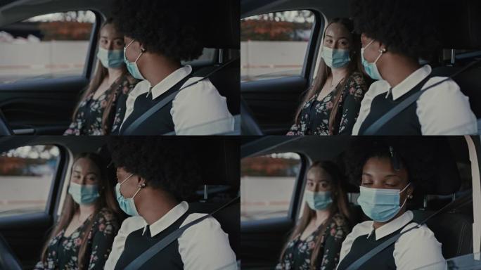 两名年轻女性在汽车上交谈并戴着保护性医用口罩