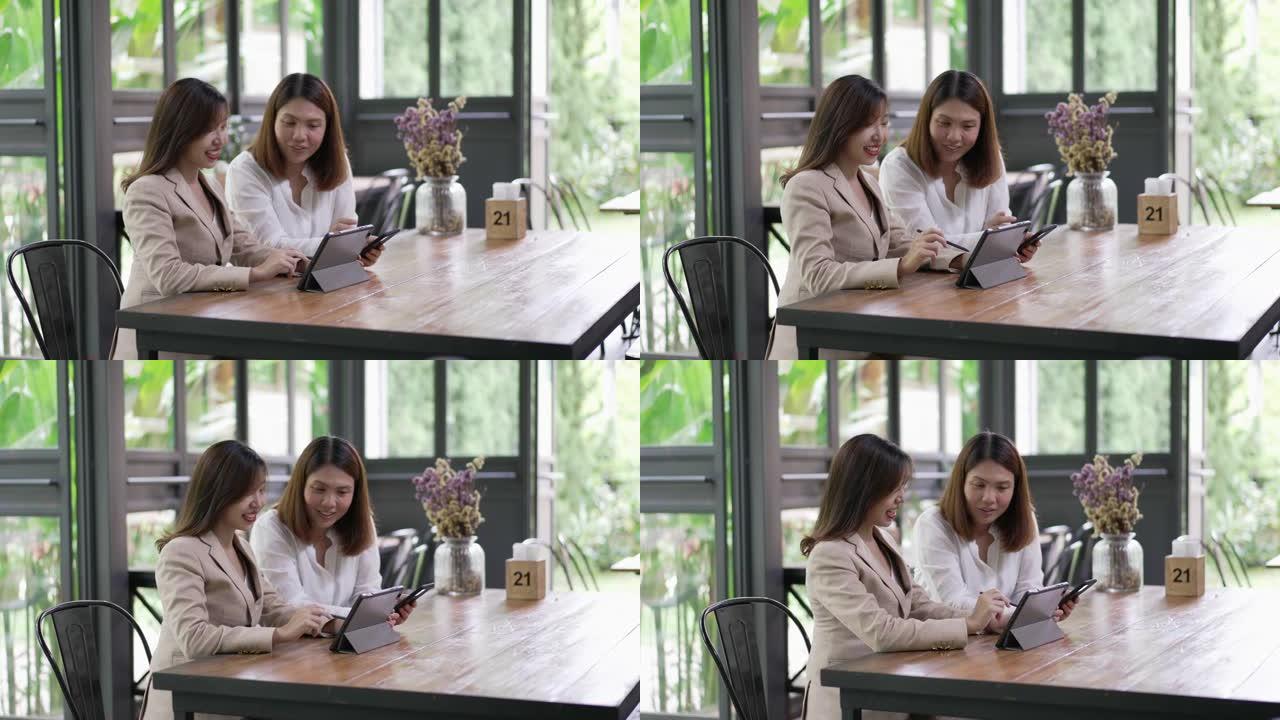 两位女商人一起在数字平板电脑上交谈和讨论