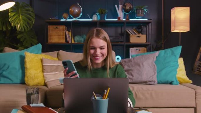 快乐年轻美丽的20多岁金发女商人使用笔记本电脑和手机一起管理密码在线工作